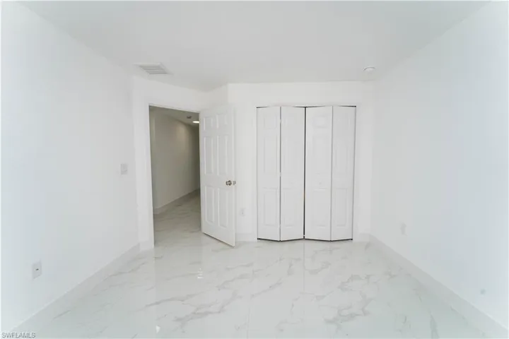 Unfurnished bedroom featuring light marble finish floors and a closet