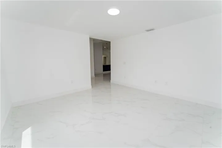 Spare room featuring light marble finish floors and baseboards