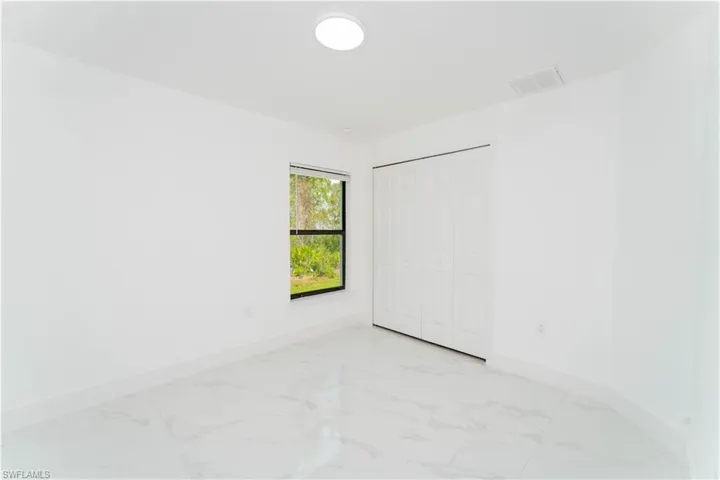 Unfurnished bedroom with light marble finish floors and a closet