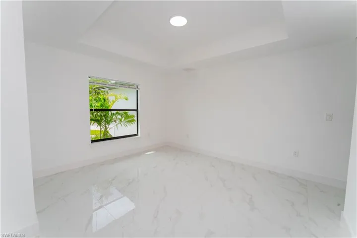 Unfurnished room featuring a tray ceiling and marble look tile flooring