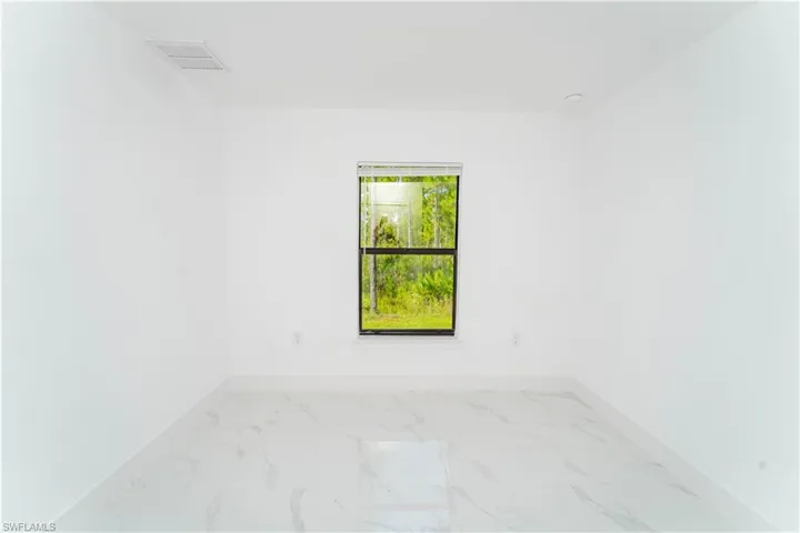 Spare room featuring light marble finish flooring and baseboards