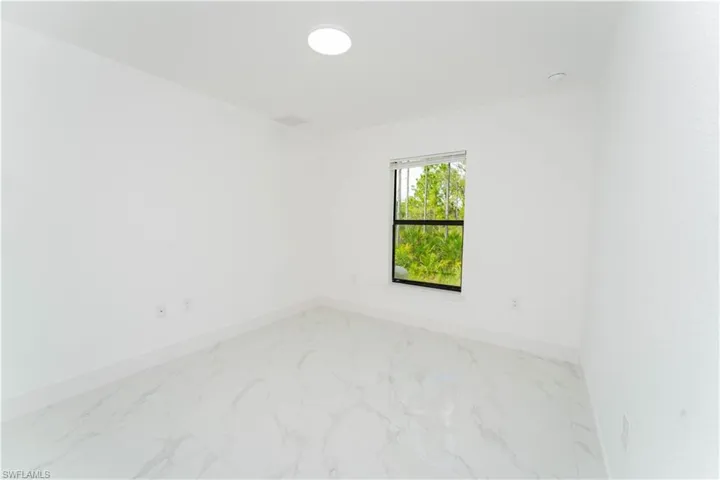 Spare room featuring light marble finish flooring and baseboards