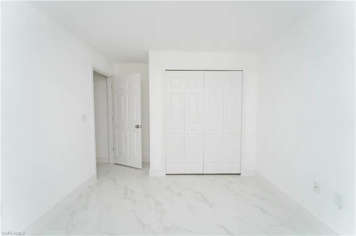 Unfurnished bedroom featuring light marble finish flooring and a closet