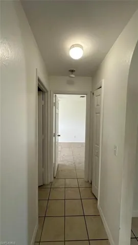 Hall featuring light tile patterned flooring and baseboards