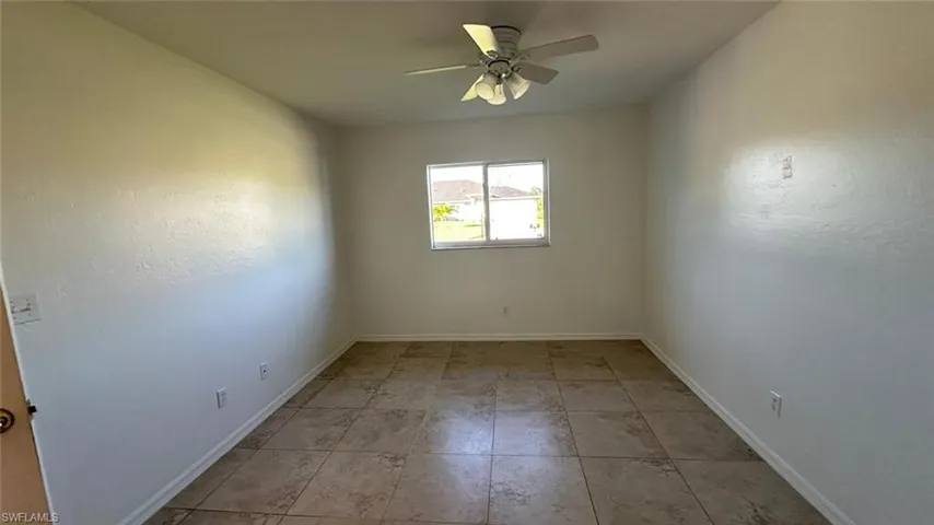 Unfurnished room with ceiling fan and light tile patterned floors
