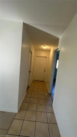 Hallway featuring light tile patterned floors and baseboards