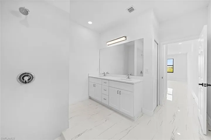 Spacious bathroom with a walk-in shower, dual vanity, and large framed mirror