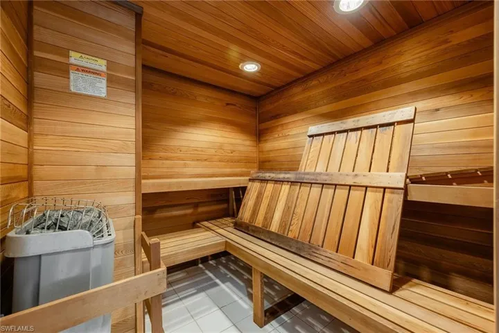 View of sauna featuring wood walls, tile patterned floors, and wooden ceiling