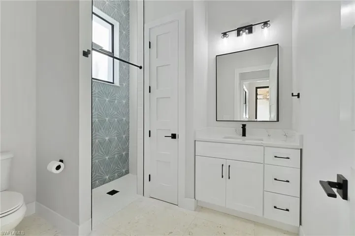 Bathroom with a tile shower, vanity, and toilet