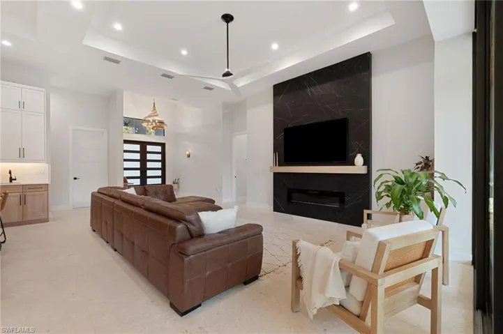 Living room with a towering ceiling, a high end fireplace, and a tray ceiling