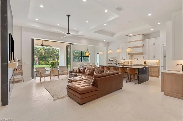 Living room featuring a towering ceiling, a raised ceiling, and sink