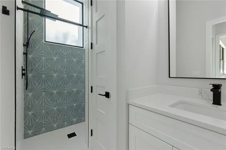 Bathroom featuring tiled shower and vanity