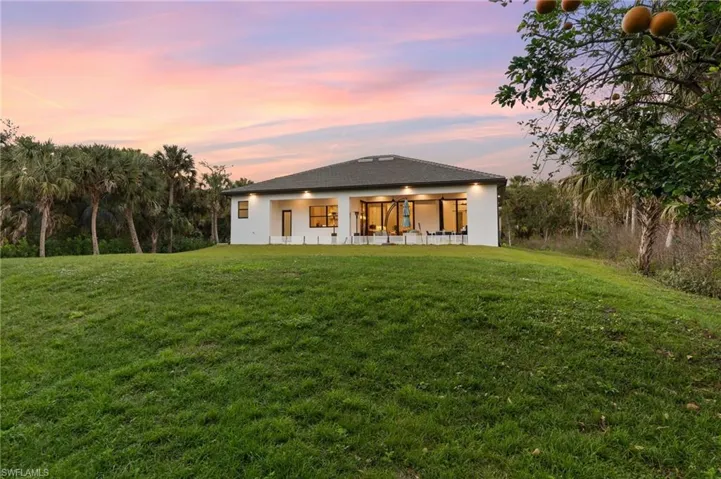 Back house at dusk featuring a yard