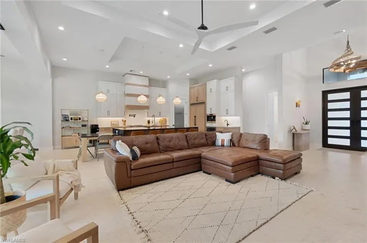 Living room featuring ceiling fan, a tray ceiling, and a high ceiling