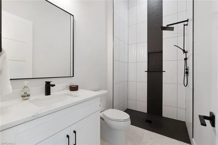 Bathroom featuring vanity, toilet, and a tile shower