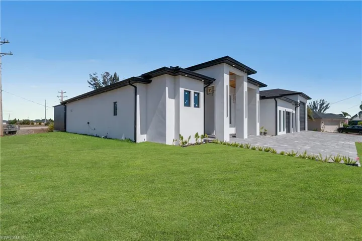 View of front facade featuring a garage, a front yard, and stucco siding