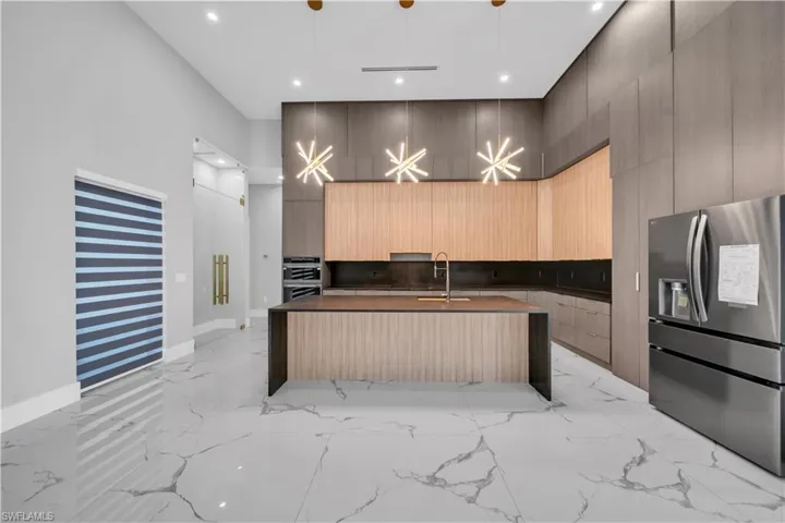 Kitchen with marble finish floor, light brown cabinets, stainless steel appliances, and modern cabinets