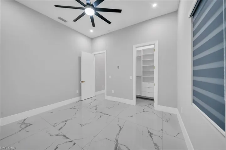 Unfurnished bedroom featuring visible vents, baseboards, a spacious closet, recessed lighting, and marble finish floor