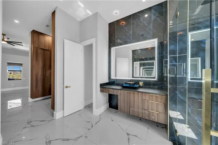 Bathroom with recessed lighting, vanity, marble finish floor, and baseboards
