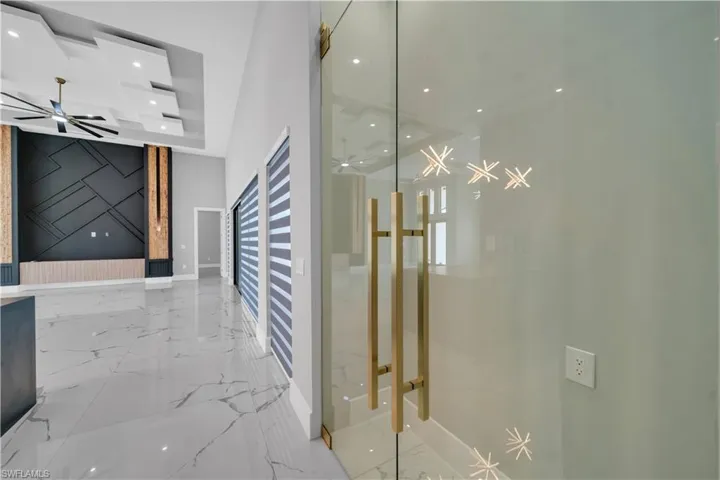 Corridor featuring marble finish floor, baseboards, a tray ceiling, and recessed lighting