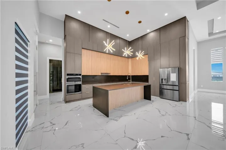 Kitchen featuring a sink, modern cabinets, marble finish floor, stainless steel appliances, and a high ceiling