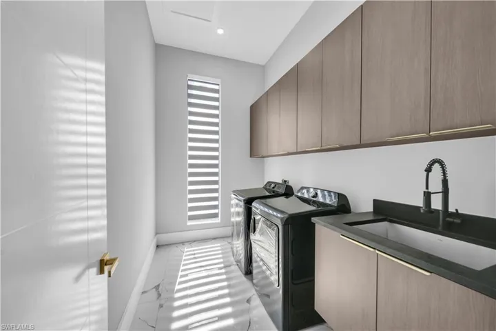 Laundry area featuring a sink, marble finish floor, cabinet space, washing machine and dryer, and baseboards