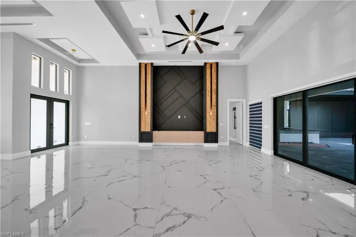 Unfurnished living room featuring ceiling fan, french doors, baseboards, and a raised ceiling