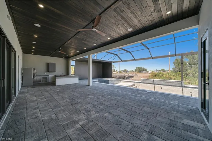 View of patio with a ceiling fan, glass enclosure, and area for grilling