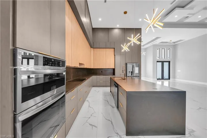 Kitchen with baseboards, recessed lighting, modern cabinets, marble finish floor, and appliances with stainless steel finishes