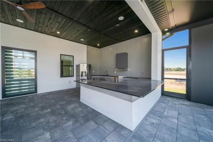Kitchen featuring stainless steel fridge with ice dispenser, dark countertops, modern cabinets, wood ceiling, and a peninsula