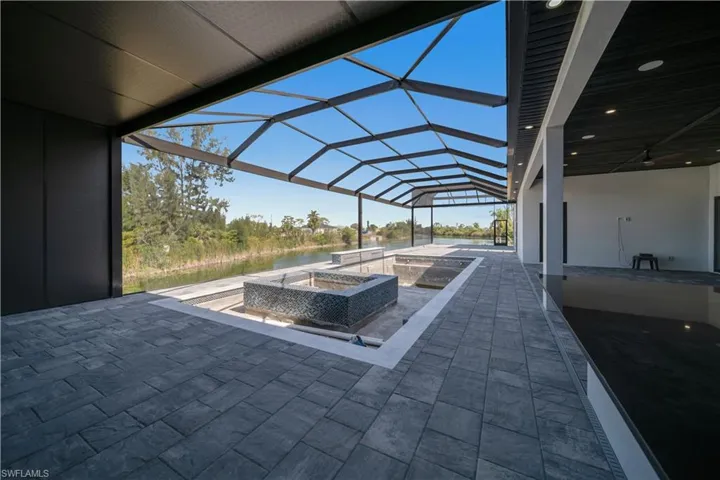 View of patio featuring a lanai, a water view, and a jacuzzi