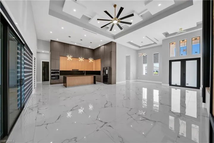 Kitchen featuring a high ceiling, a ceiling fan, modern cabinets, a center island, and open floor plan