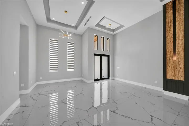 Empty room featuring recessed lighting, marble finish floor, a tray ceiling, a skylight, and baseboards