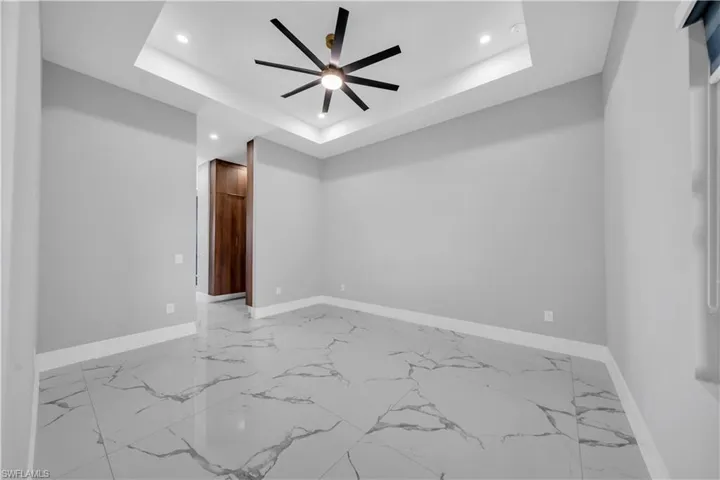 Unfurnished room with marble finish floor, baseboards, a tray ceiling, and recessed lighting