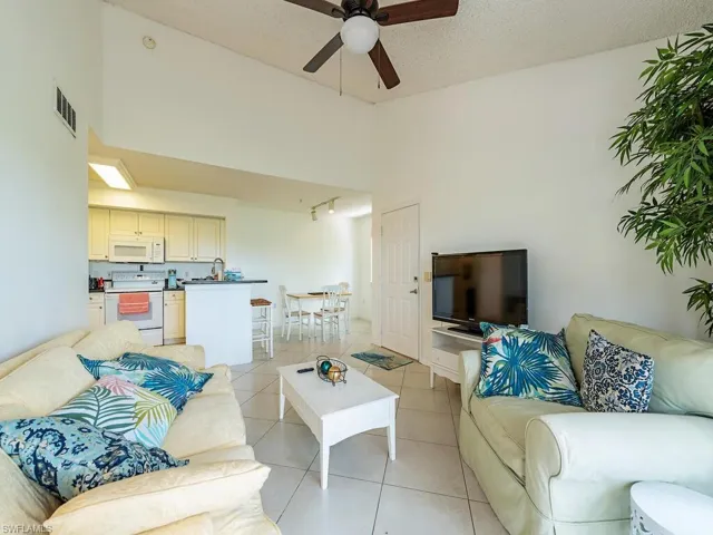 Tiled living room featuring ceiling fan, a towering ceiling, and a textured ceiling