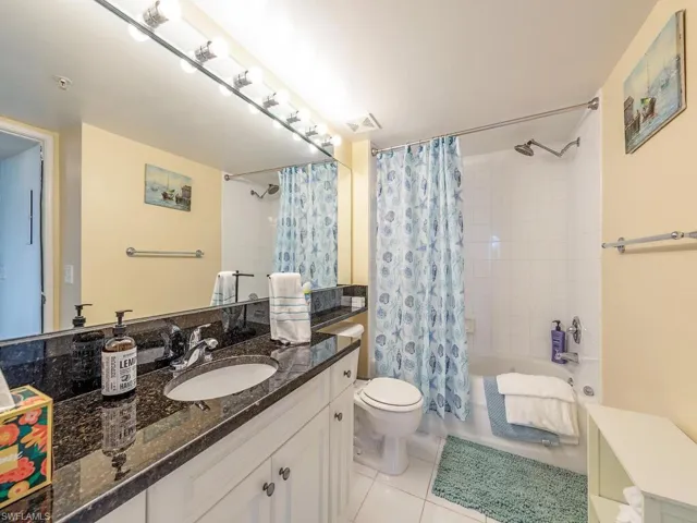 Full bathroom with tile flooring, toilet, vanity, and shower / bath combo
