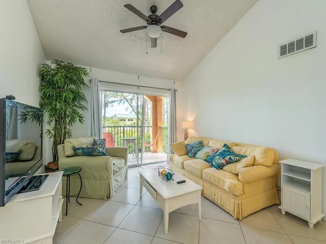 Living room with high vaulted ceiling, a textured ceiling, ceiling fan, and light tile floors