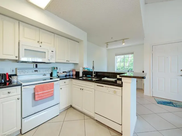 Kitchen featuring kitchen peninsula, rail lighting, white cabinetry, sink, and white appliances