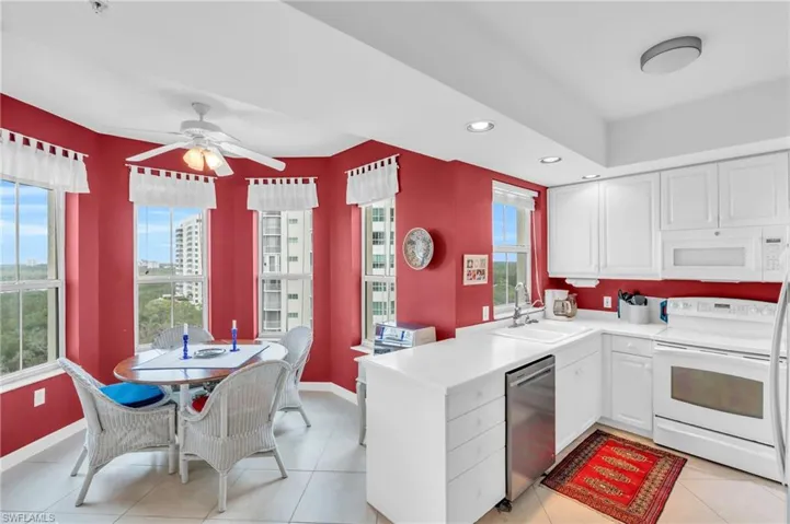 Kitchen featuring white cabinets, plenty of natural light, white appliances, and sink