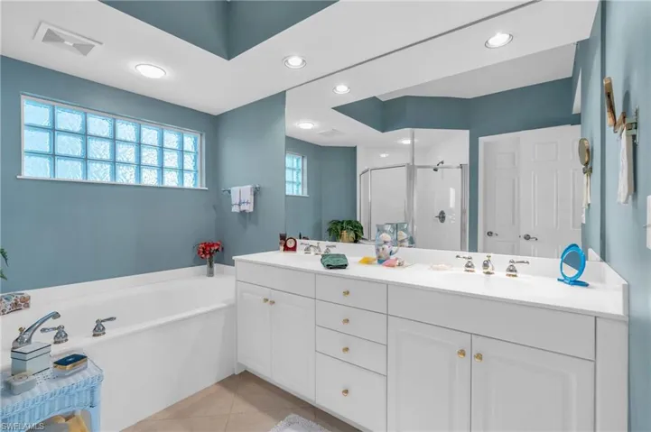 Bathroom featuring tile patterned floors, vanity, and separate shower and tub