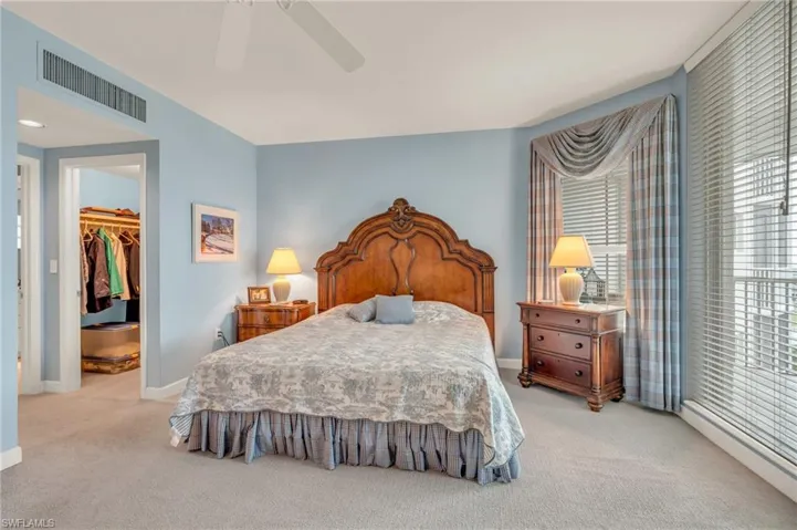 Carpeted bedroom with a walk in closet, ceiling fan, and a closet