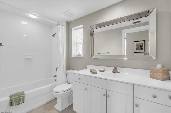 Full bathroom with tile patterned flooring, vanity, toilet, and shower / bath combo with shower curtain
