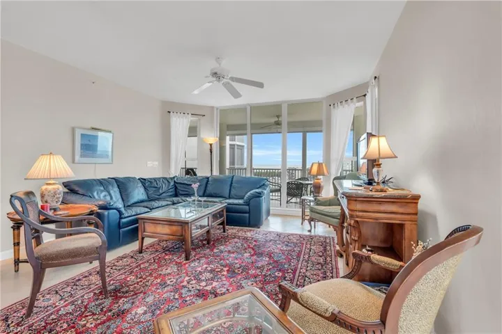 Living room featuring floor to ceiling windows, ceiling fan, and light tile patterned floors