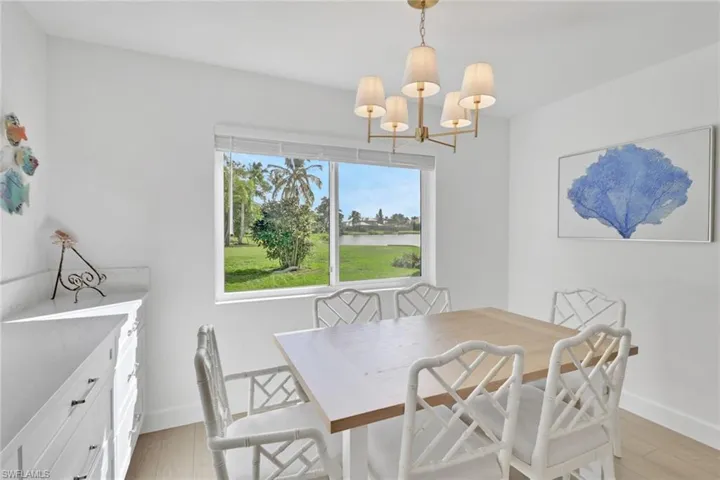Dining area with light wood-type flooring, a water view, and a chandelier