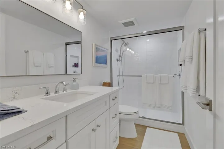 Full bathroom with vanity, a stall shower, and light wood-type flooring