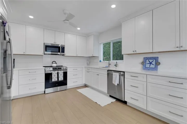 Kitchen with appliances with stainless steel finishes, white cabinetry, recessed lighting, light wood-style floors, and ceiling fan
