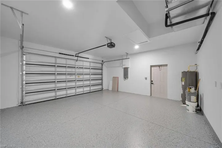 Garage featuring water heater, electric panel, and a garage door opener