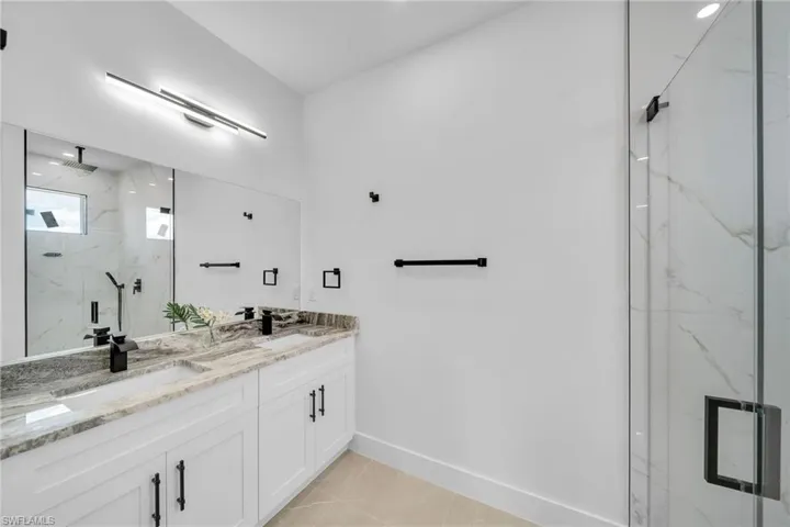 Bathroom featuring tile patterned floors, a shower with door, and vanity