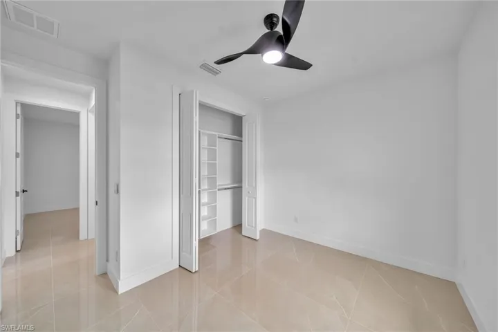 Unfurnished bedroom with light tile patterned floors, ceiling fan, and a closet
