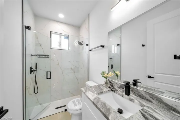 Bathroom featuring a shower with shower door, vanity, and toilet